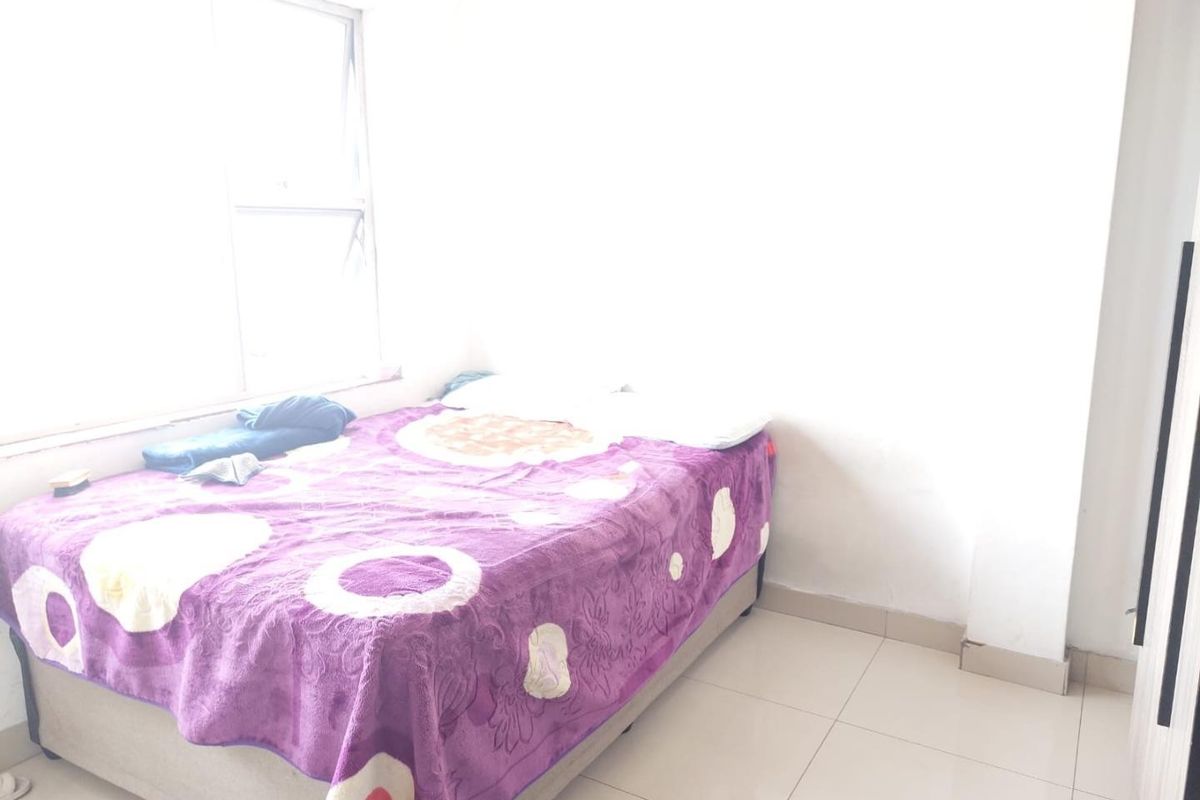 A simple bedroom featuring tiled flooring and a large window, providing natural light to the space.