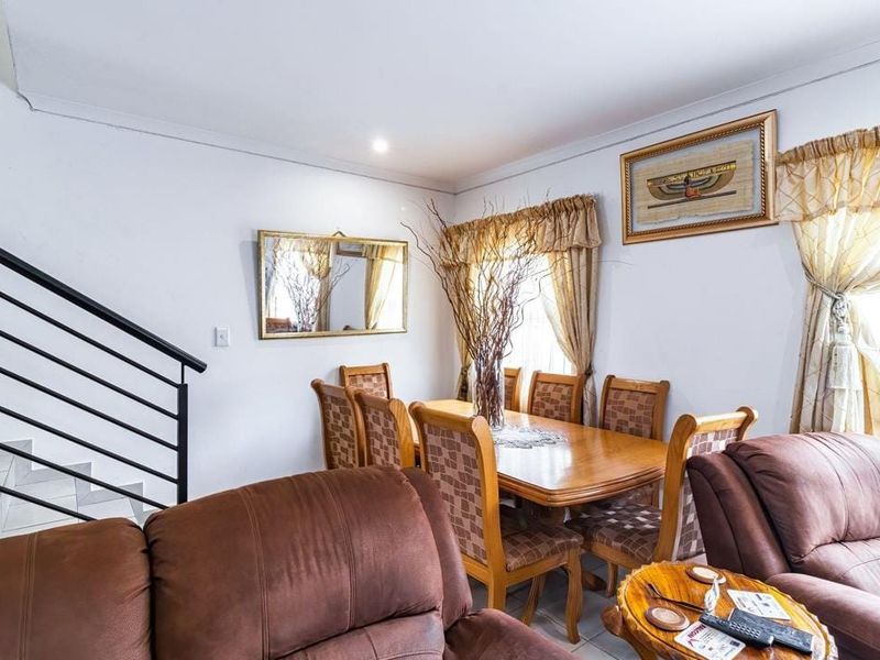 Open plan living and dining area featuring tiled flooring and a staircase with a modern metal railing.