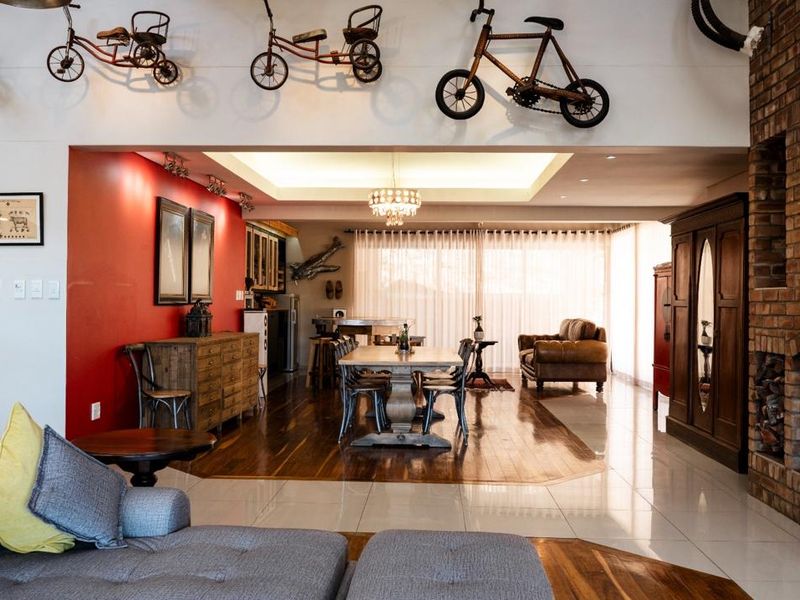 Spacious open-plan living and dining area featuring a brick fireplace, recessed ceiling lighting, and a combination of hardwood and tiled flooring.
