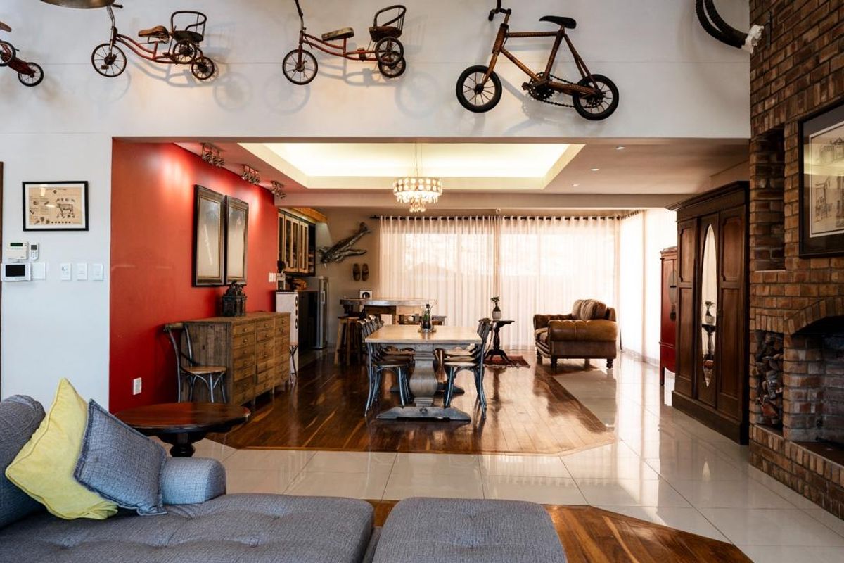 Spacious open-plan living and dining area featuring a brick fireplace, recessed ceiling lighting, and a combination of hardwood and tiled flooring.