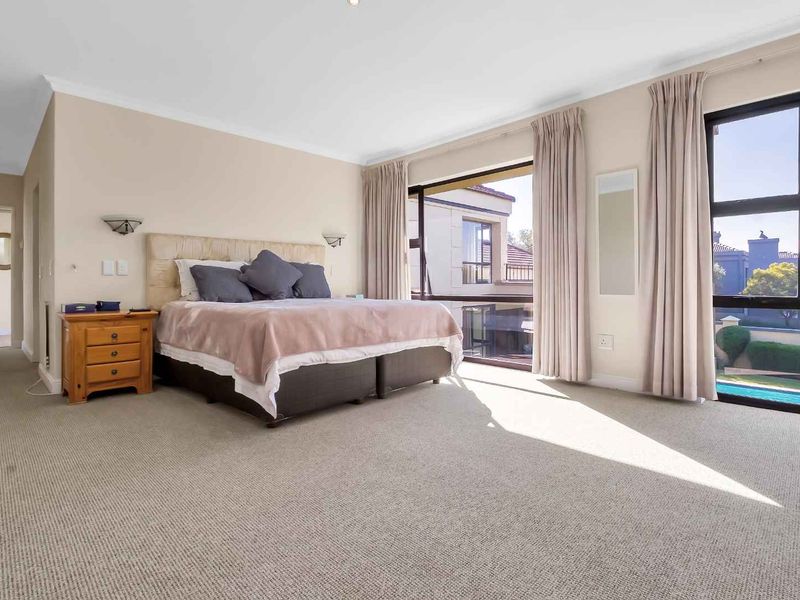 Spacious bedroom featuring large windows with natural light, neutral wall tones, and carpeted flooring, offering a comfortable and bright living space.