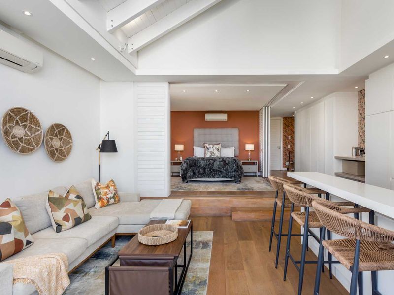 Spacious open-plan living area featuring timber flooring, exposed ceiling beams, and a seamless transition to the elevated bedroom suite.