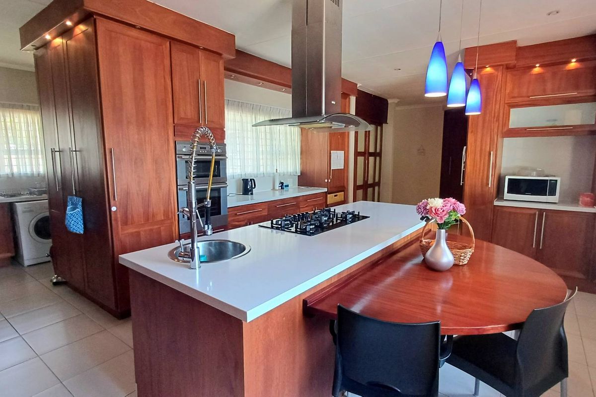 Spacious kitchen featuring extensive wood cabinetry, a large central island with a gas cooktop, integrated appliances, and stone countertops.