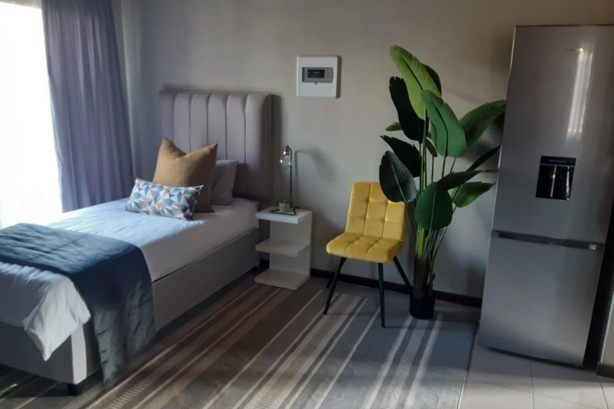 A well-maintained bedroom featuring neutral wall tones, tiled flooring, and large windows with curtain tracks, providing a comfortable and functional living space.