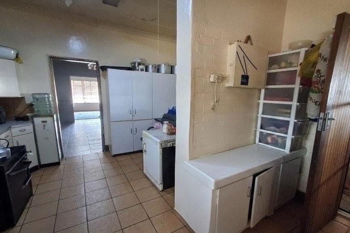 A functional kitchen area featuring built-in cabinetry and tiled flooring, offering potential for modernization and aesthetic updates.