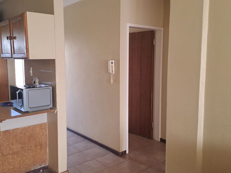 Open plan area featuring tiled flooring, a breakfast counter, built-in cabinetry, and an intercom system, connecting to a hallway.