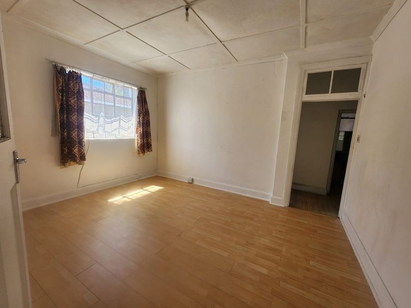 An empty bedroom featuring laminate flooring and a tiled ceiling, offering a blank canvas for renovation or interior design updates.