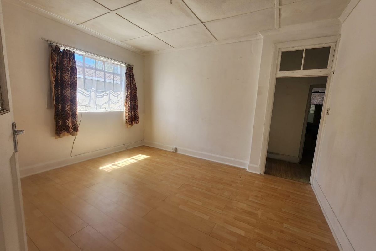 An empty bedroom featuring laminate flooring and a tiled ceiling, offering a blank canvas for renovation or interior design updates.
