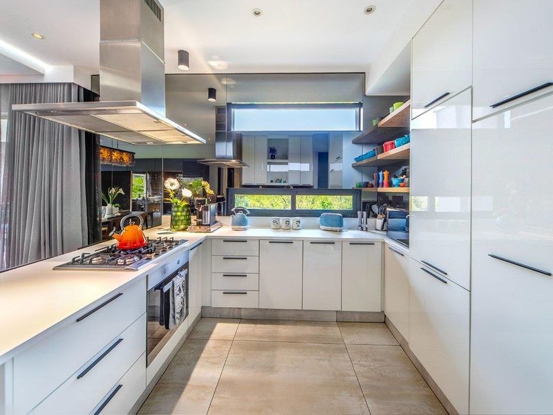 Modern kitchen featuring high-gloss white cabinetry, stone countertops, integrated appliances, a mirrored splashback, and a gas cooktop with a stainless steel extractor fan.