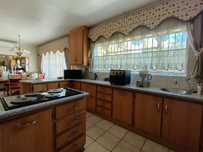 A functional kitchen featuring traditional wooden cabinetry, laminate countertops, an integrated electric hob, and tiled flooring, offering a classic layout with ample storage space.