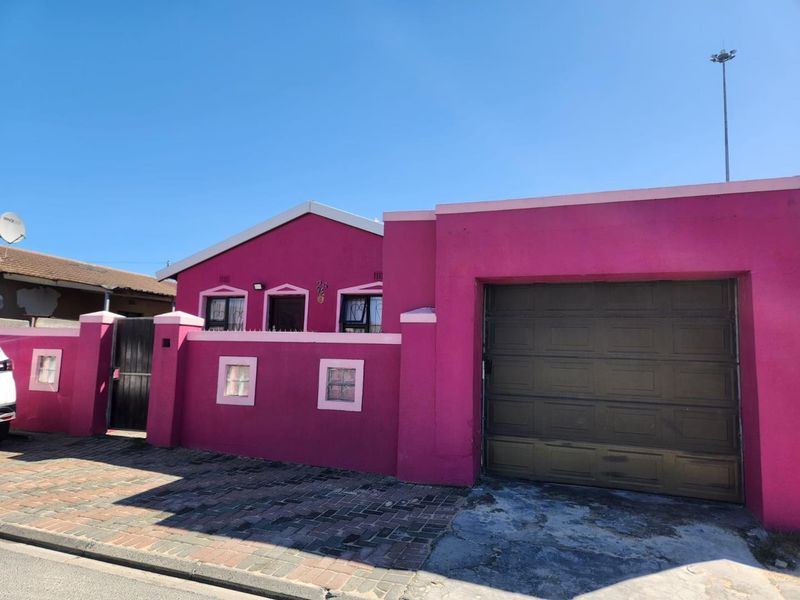 Front elevation of a residential property featuring a garage, boundary wall, and paved driveway access.