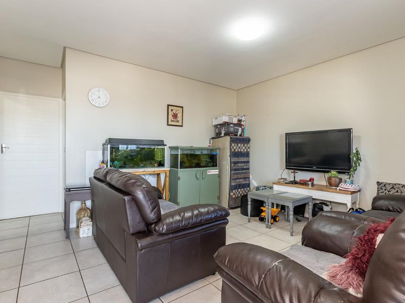 A living room area featuring neutral wall finishes and tiled flooring, providing a functional space for relaxation.