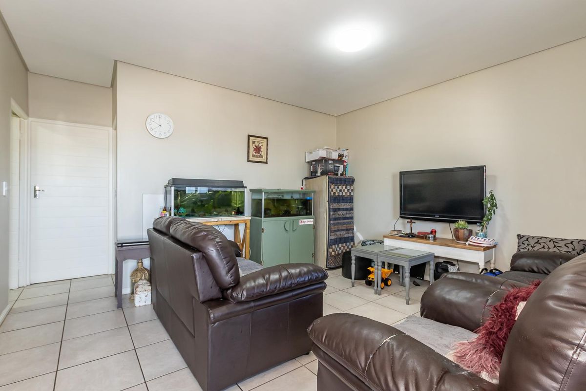 A living room area featuring neutral wall finishes and tiled flooring, providing a functional space for relaxation.