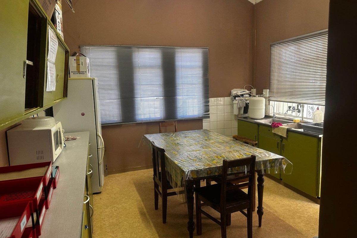 A dated kitchen featuring built-in cabinetry, a double basin sink, and tiled splashbacks, offering significant potential for modernization and renovation.