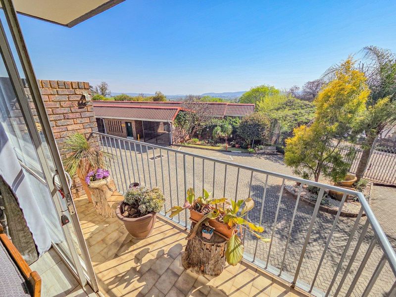 A sunny balcony featuring tiled flooring and a metal balustrade, offering an elevated view of the complex grounds and surrounding neighborhood.