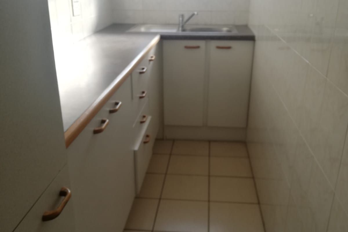 A compact, functional kitchen featuring white built-in cabinetry, tiled walls, and tiled flooring, providing a clean and practical workspace.