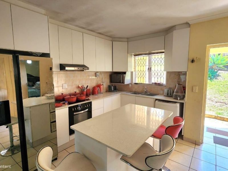 A dated kitchen featuring white cabinetry, a central island, and direct access to the rear garden area.