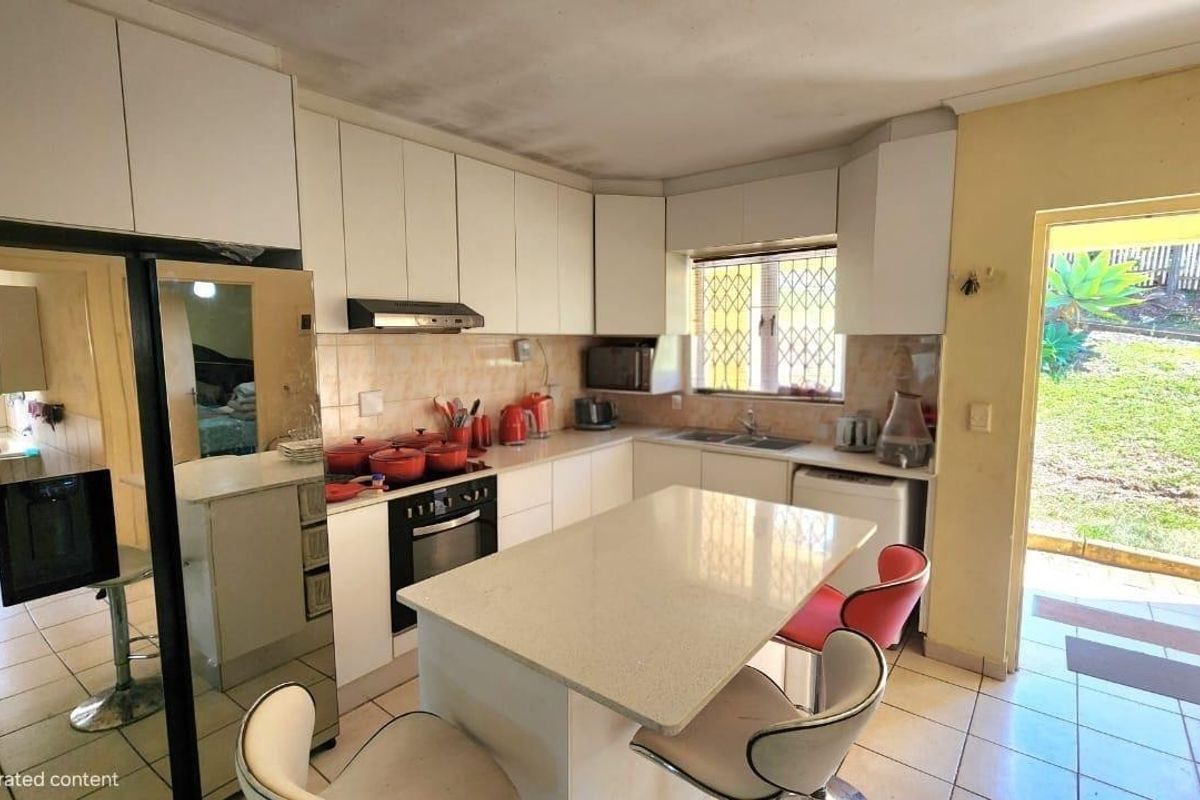 A dated kitchen featuring white cabinetry, a central island, and direct access to the rear garden area.