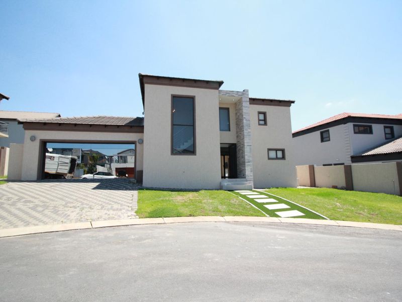 Modern double-storey residential home featuring a double garage, paved driveway, and contemporary stone-clad architectural detailing.