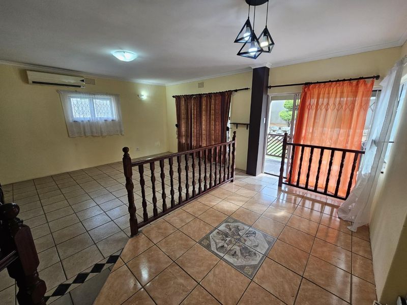 Spacious living area featuring ceramic tiled flooring, a split-system air conditioner, and direct access to an outdoor space through a sliding glass door.
