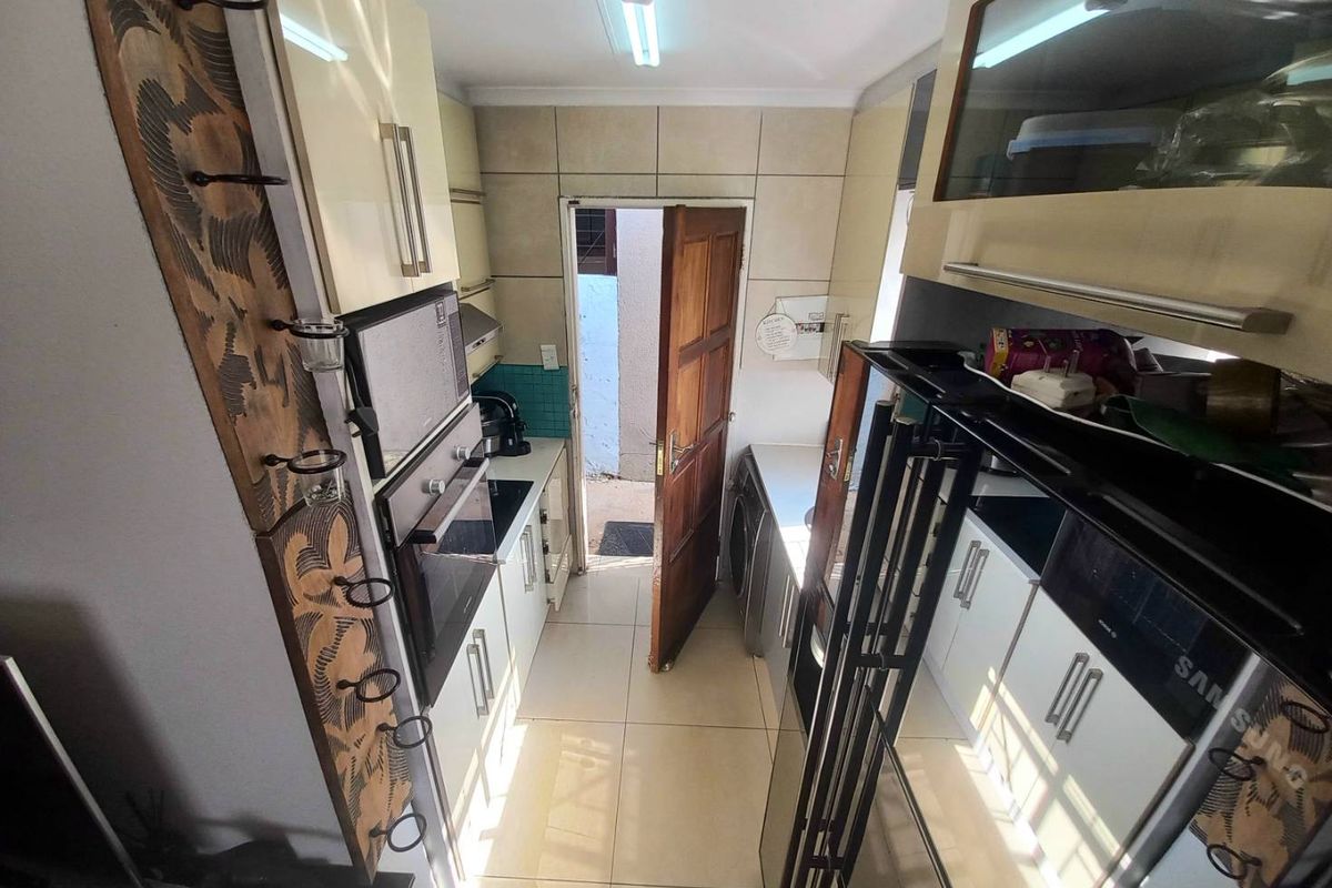 A compact galley-style kitchen featuring built-in cabinetry, integrated oven, and direct access to an exterior area.