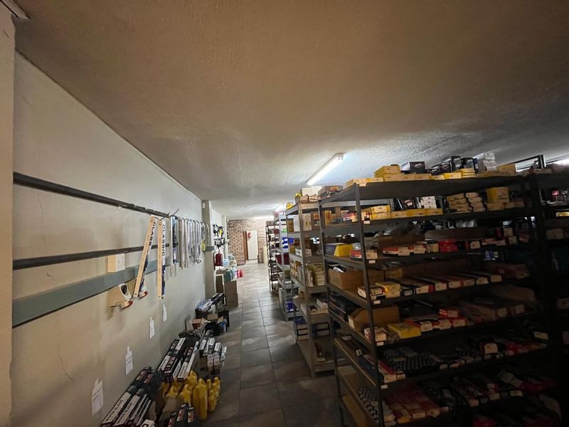 A functional utility or storage space featuring tiled flooring, fluorescent lighting, and wall-mounted display rails for inventory organization.