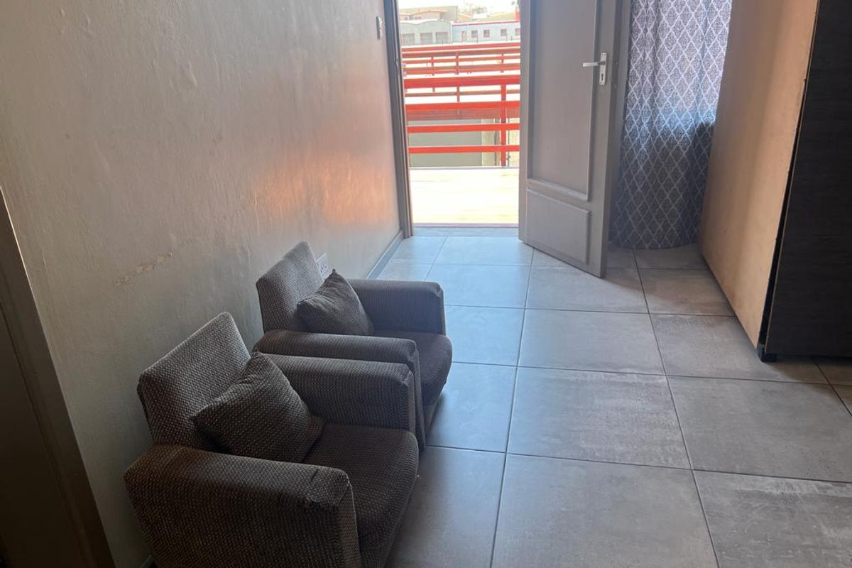 A functional living space featuring large format floor tiles and direct access to an outdoor balcony area.