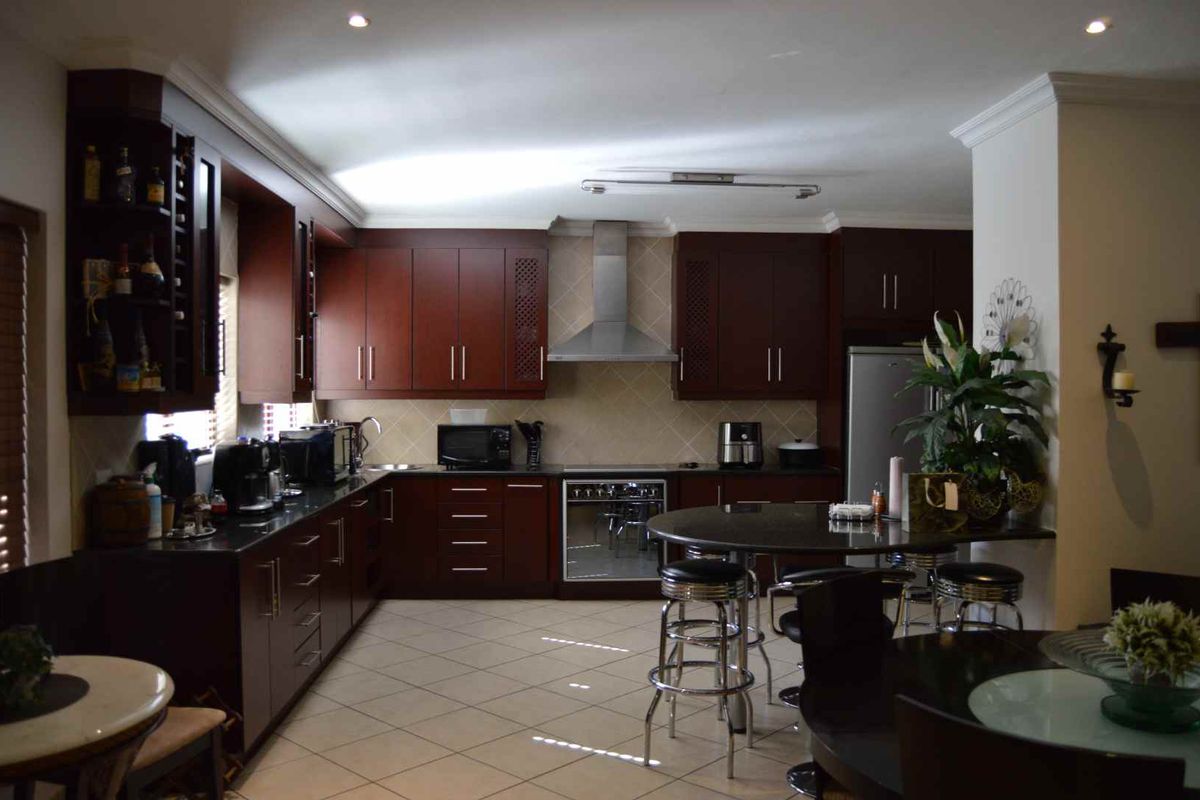 Spacious kitchen featuring dark wood cabinetry, granite countertops, a stainless steel extractor fan, and a built-in oven with a tiled backsplash.