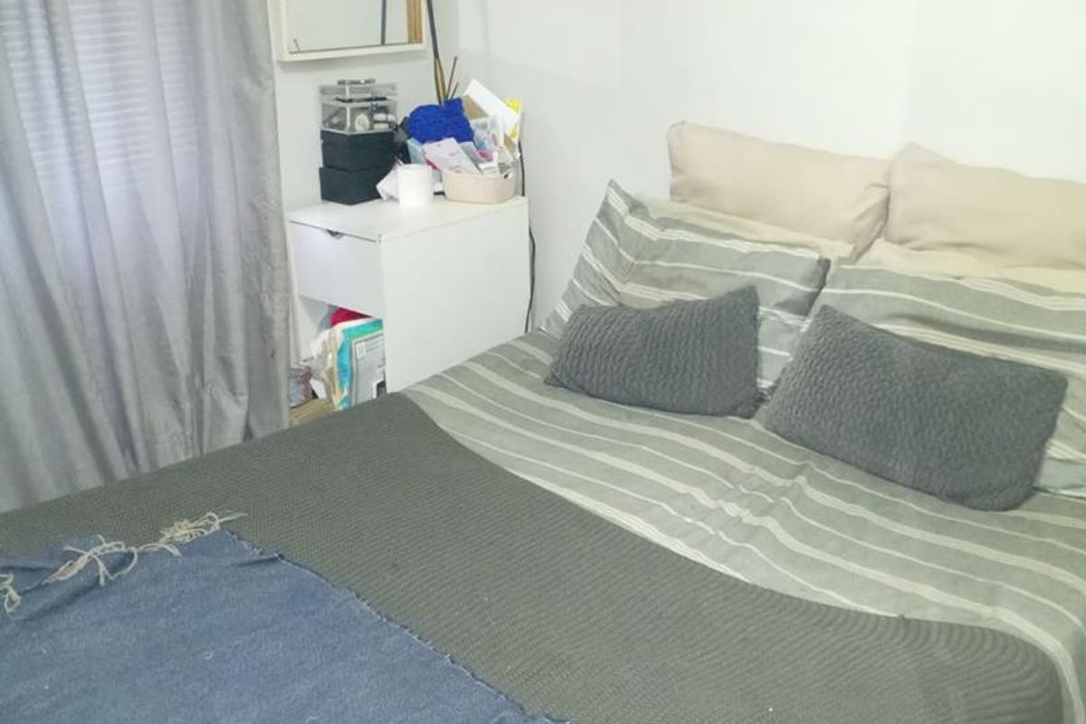 A functional bedroom featuring tiled flooring and neutral wall finishes, providing a simple and practical sleeping space.