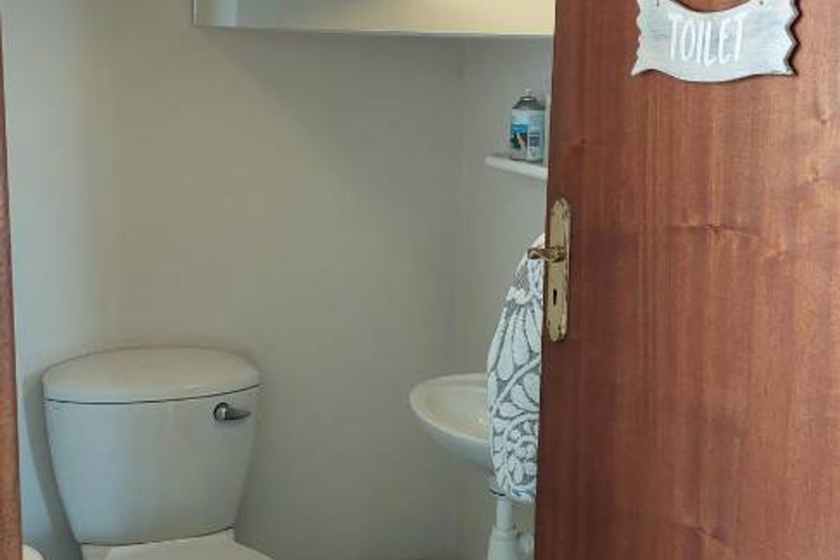 A compact guest bathroom featuring a white toilet, wall-mounted basin, and tiled flooring.