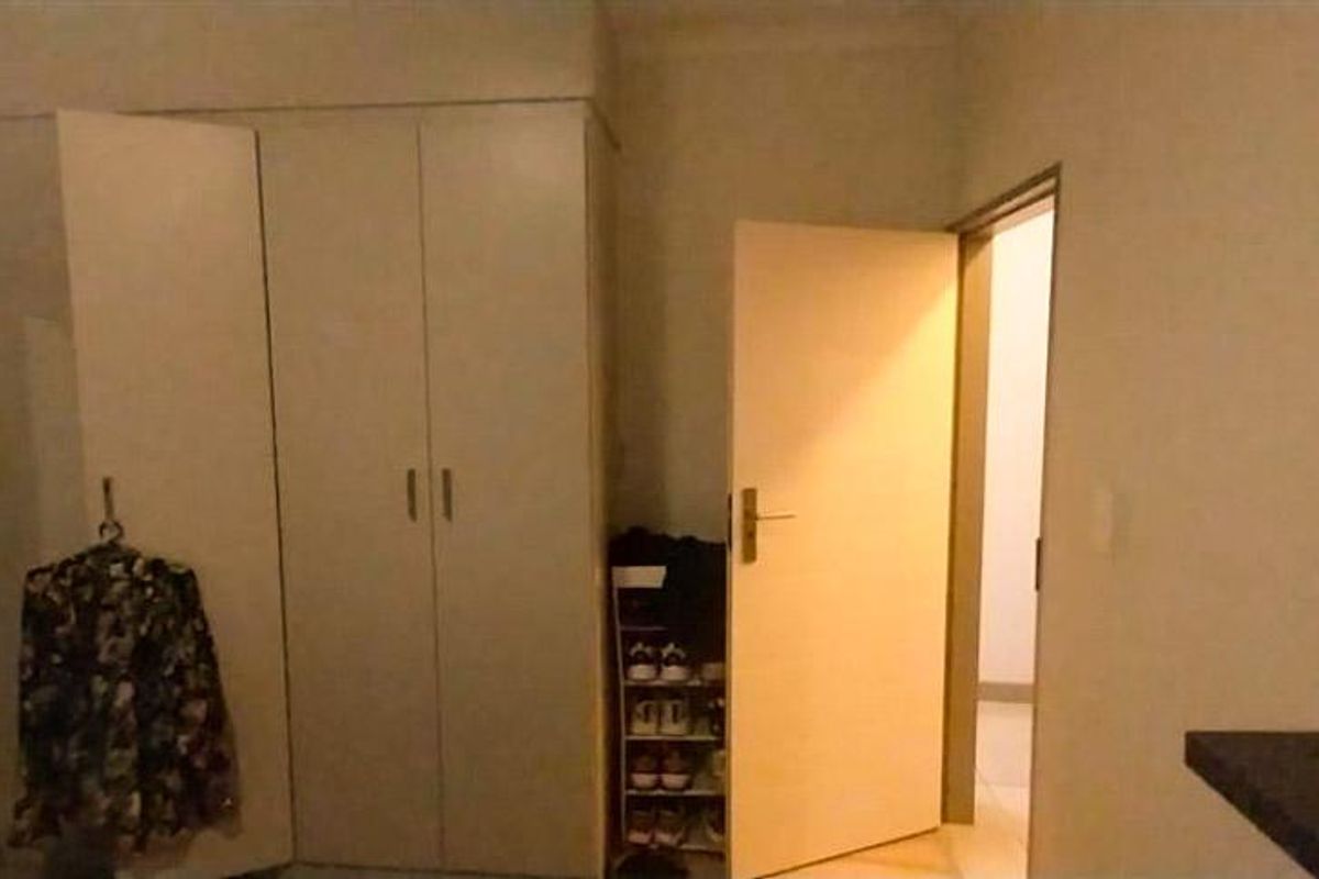 A bedroom interior featuring built-in cupboards and a doorway leading to an adjacent hallway.