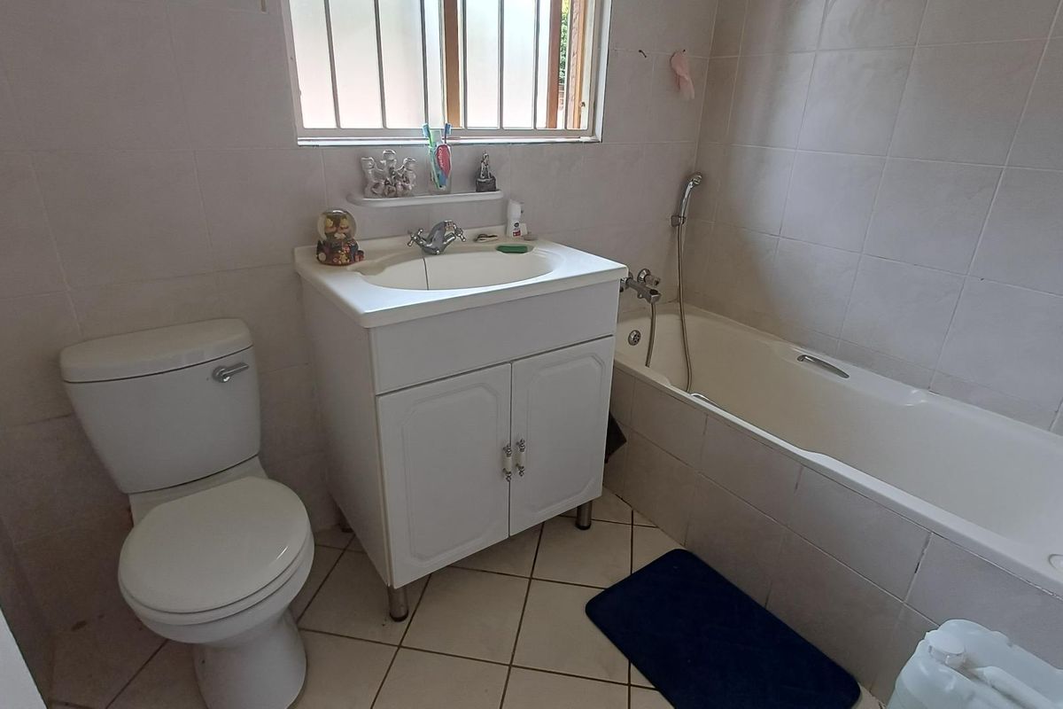 A functional bathroom featuring a built-in vanity, a standard bathtub with shower attachment, and tiled walls and flooring.
