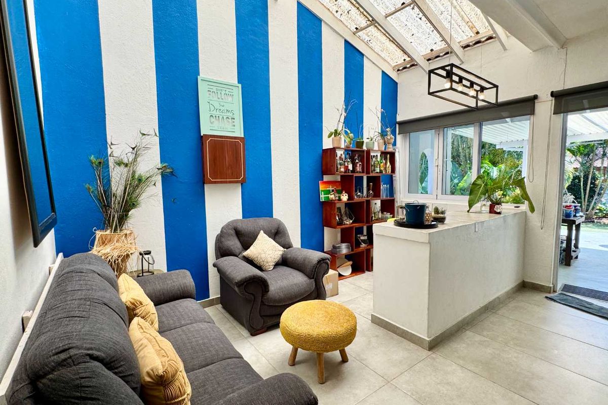 A bright living area featuring a high-pitched translucent roof, tiled flooring, and a built-in service counter, offering a seamless transition to the outdoor space.