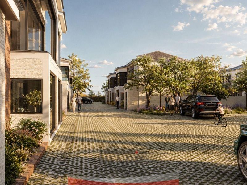 A modern townhouse complex featuring a paved driveway, brick facade architecture, and established landscaping in a residential setting.