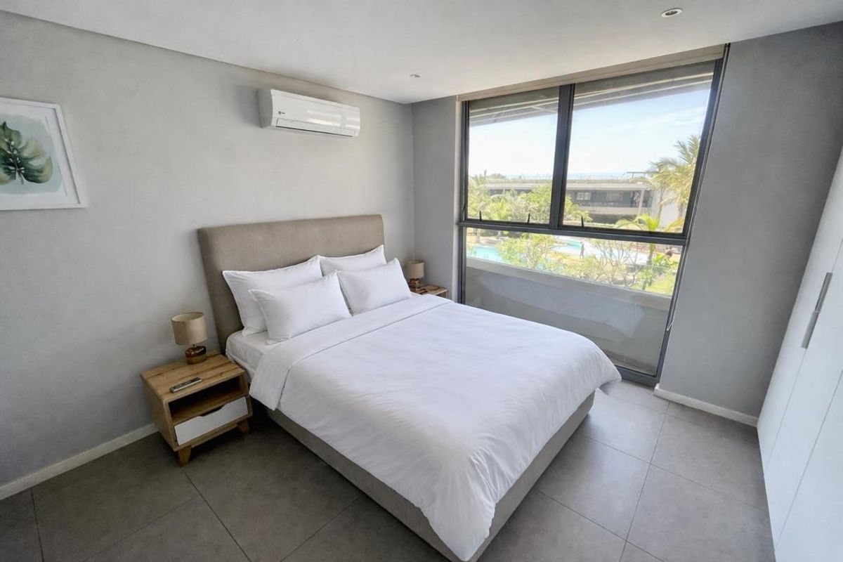 Modern bedroom featuring tiled flooring, an air conditioning unit, and a large window with views of the complex pool area.