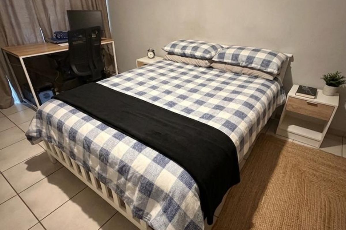 A functional bedroom featuring tiled flooring and neutral wall finishes, providing a comfortable space with natural light access.