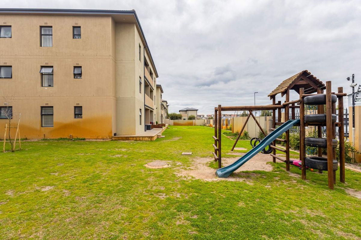 Rear view of the apartment complex featuring a communal lawn area and a playground for residents.