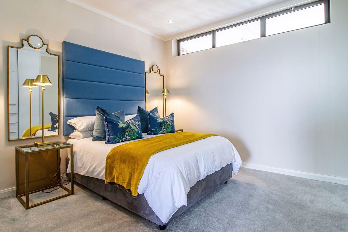 A well-maintained bedroom featuring neutral carpeting, recessed ceiling lighting, and a high-level clerestory window providing natural light.