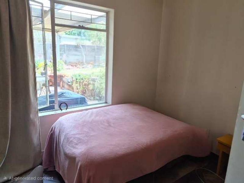 A bedroom featuring a large window with natural light, overlooking the rear garden area.