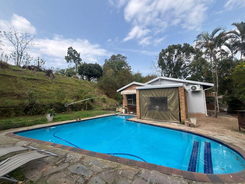 Outdoor pool area featuring a swimming pool with paved surround, brick exterior wall, and an installed split-system air conditioning unit.