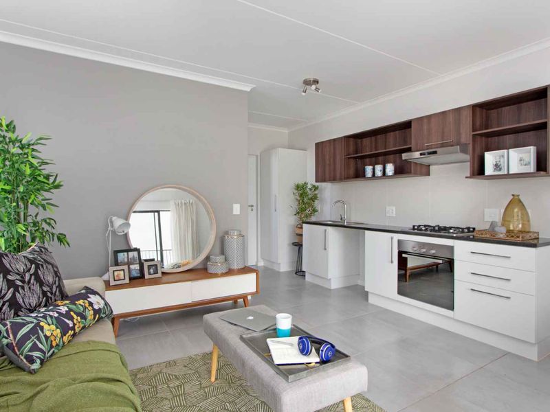Modern open-plan living area featuring a contemporary kitchen with built-in cabinetry, gas hob, oven, and extractor fan, seamlessly integrated with the living space.
