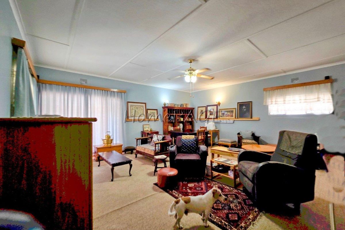 A spacious living room featuring a ceiling fan, carpeted flooring, and large windows that provide ample natural light.