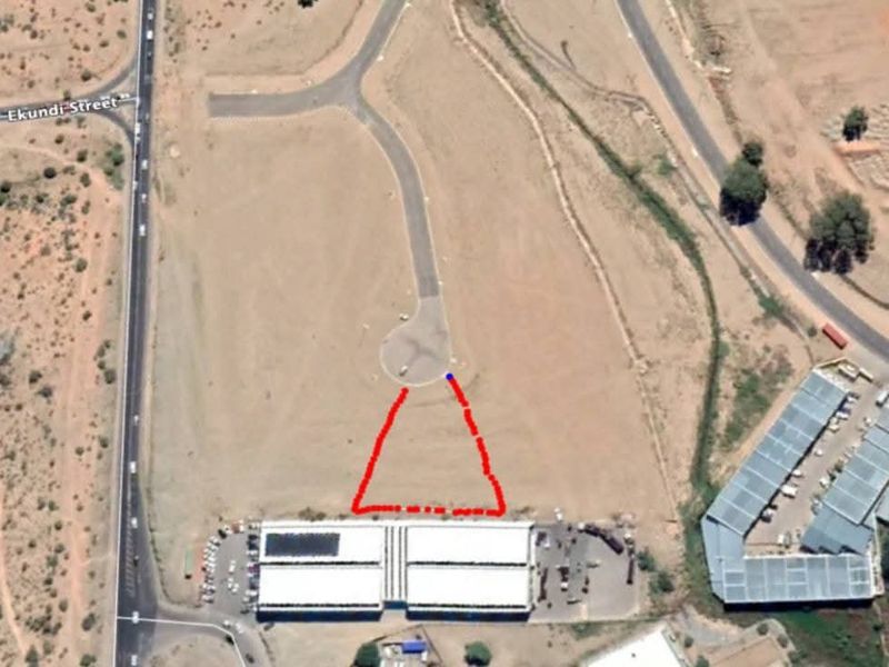 Aerial view of an industrial property site featuring a warehouse building with paved access and road frontage.