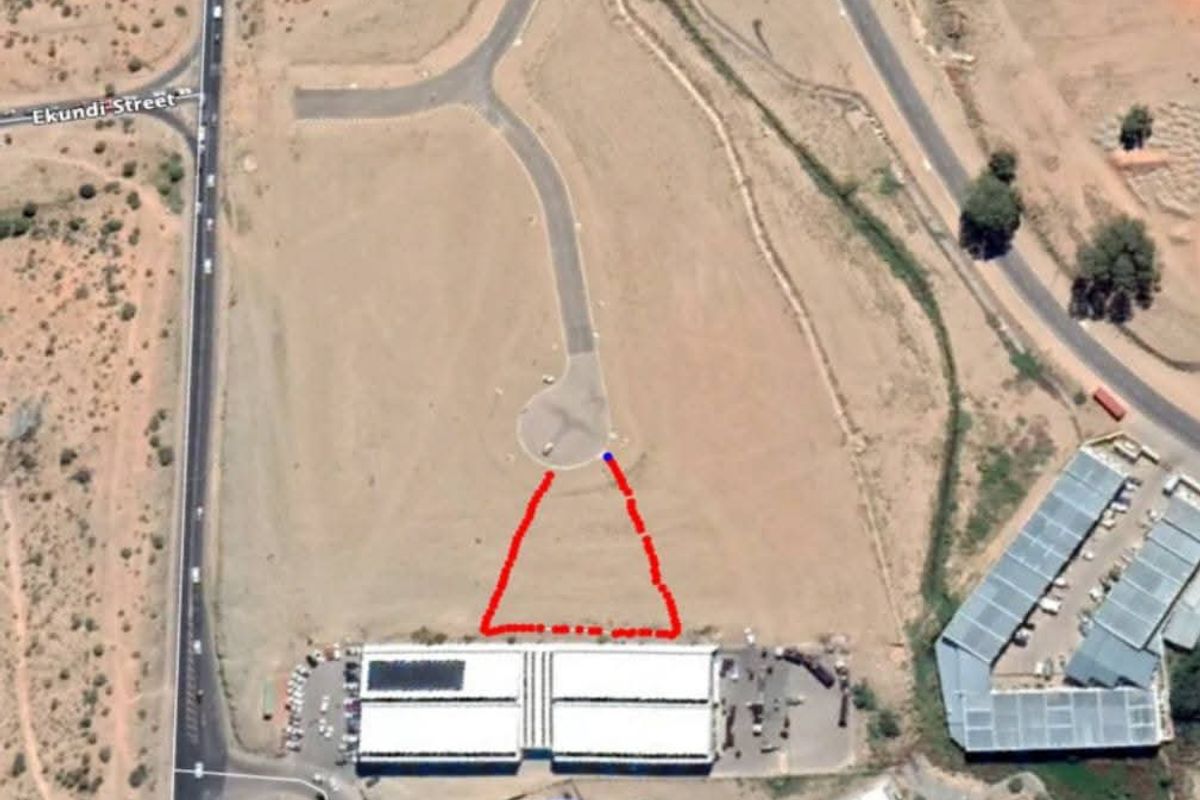 Aerial view of an industrial property site featuring a warehouse building with paved access and road frontage.