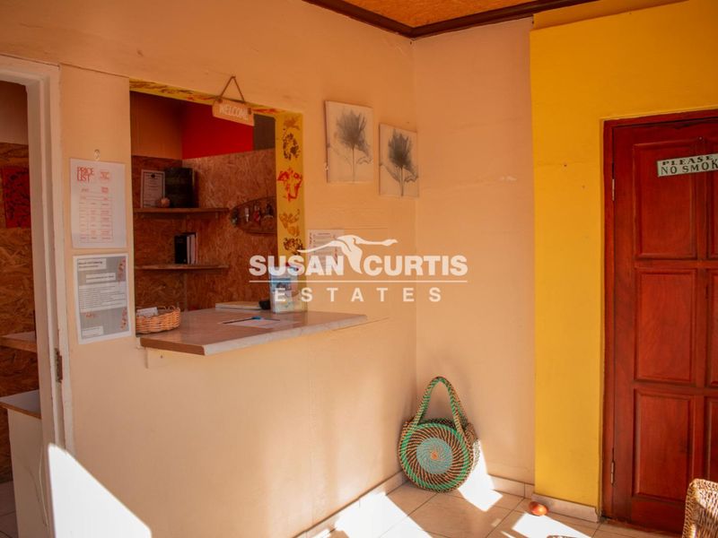 A functional reception or entry area featuring a service counter, built-in shelving, and a solid timber door.
