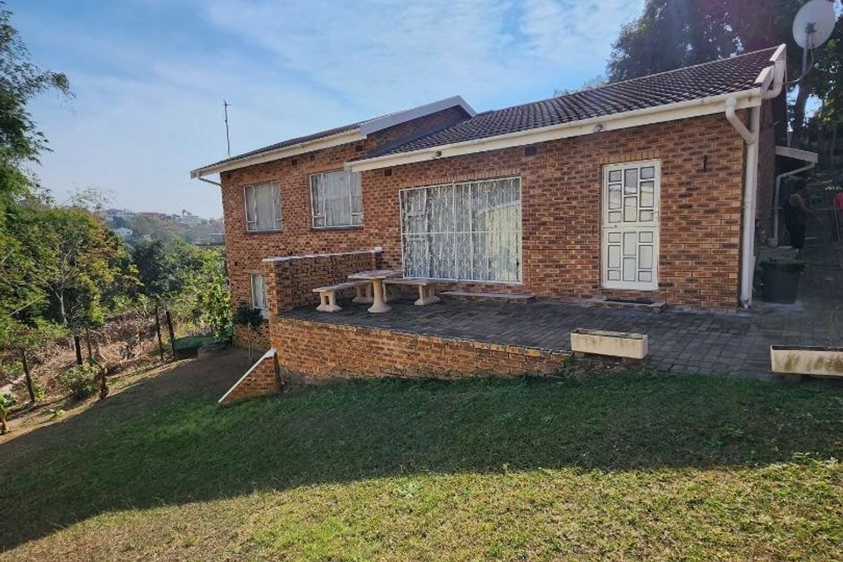 Rear view of a brick house featuring a paved patio area and surrounding lawn, showing standard residential construction and exterior finishes.