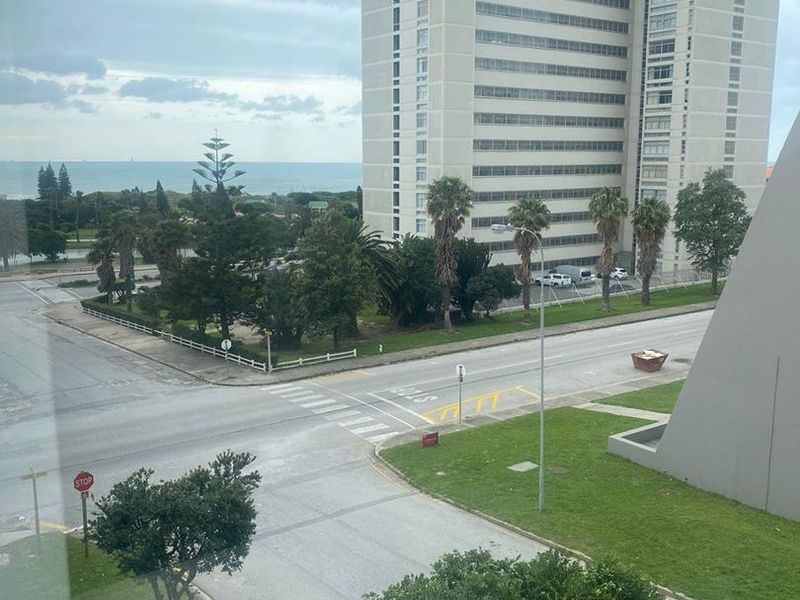 An elevated view overlooking the surrounding neighbourhood, street intersection, and distant coastal horizon.