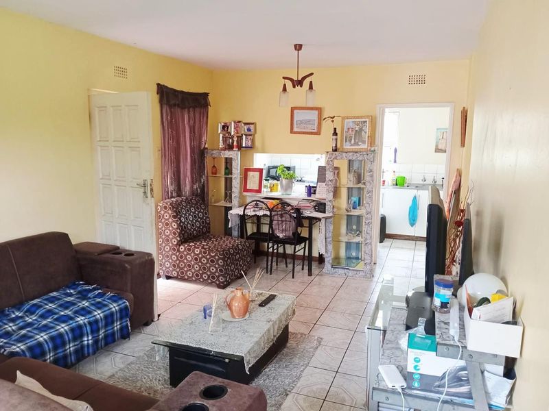 Open plan living area featuring tiled flooring and a pass-through window connecting to the kitchen space.