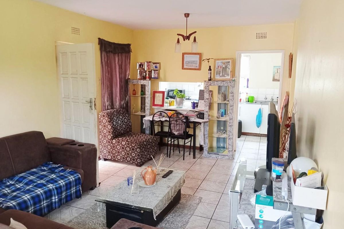 Open plan living area featuring tiled flooring and a pass-through window connecting to the kitchen space.