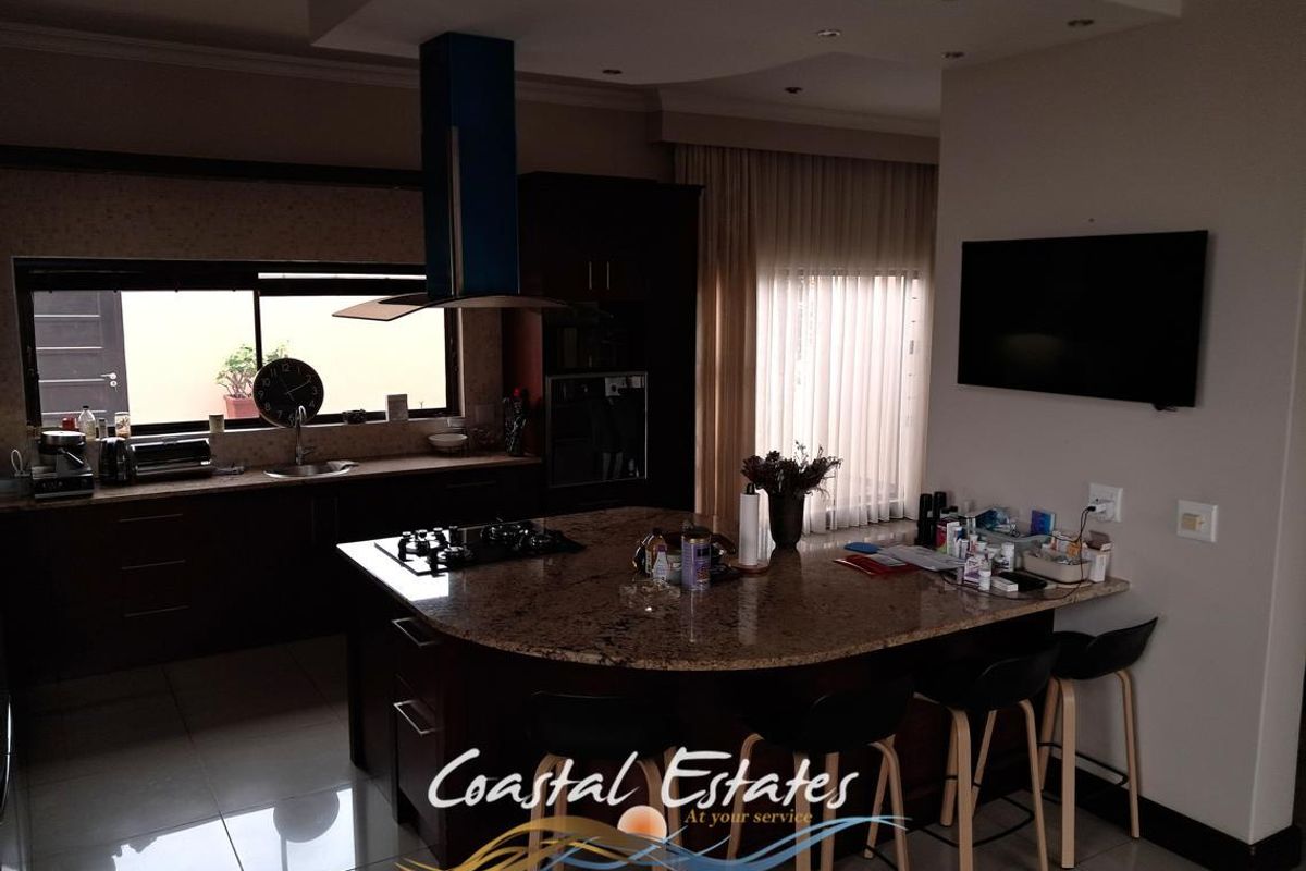 Modern kitchen featuring a large granite island with a built-in gas hob, dark cabinetry, and recessed ceiling lighting.